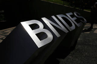 FILE PHOTO: Man walks past the logo of Brazilian Development Bank (BNDES) at the entrance of its headquarters in Rio de Janeiro