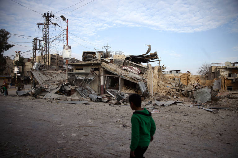 Criança caminha perto de construções destruídas por ataques na cidade de Douma; ONU pediu cessar-fogo para ajuda humanitária