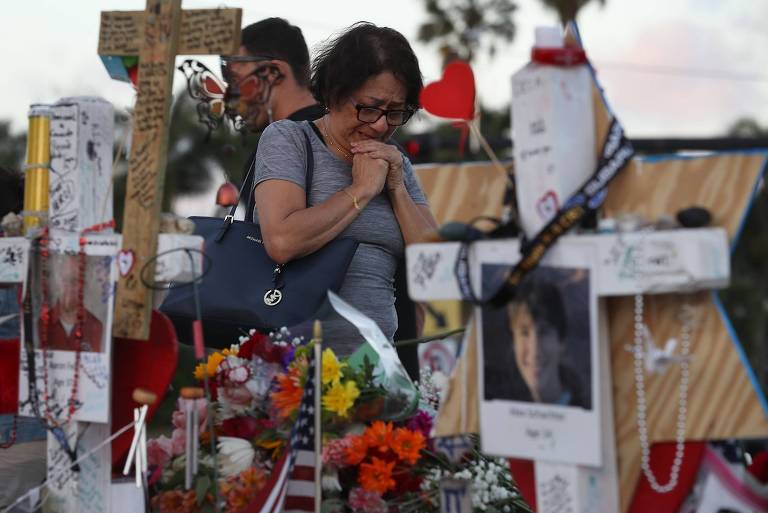 Mulher chora ao visitar o memorial das vítimas do ataque a tiros à escola Marjory Stoneman Douglas, em Parkland, na Flórida