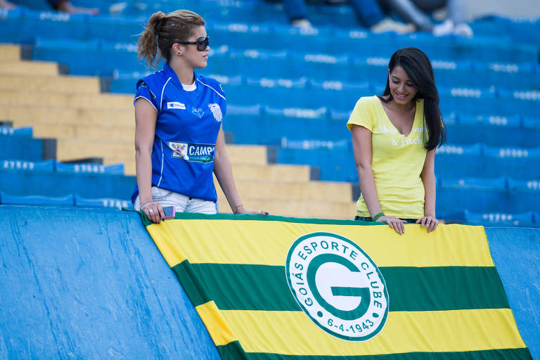Torcedora ao lado de bandeira com o símbolo do Goiás no estádio Serra Dourada