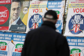FILE PHOTO:Man stands to look the electoral posters in Pomigliano D'Arco, near Naples