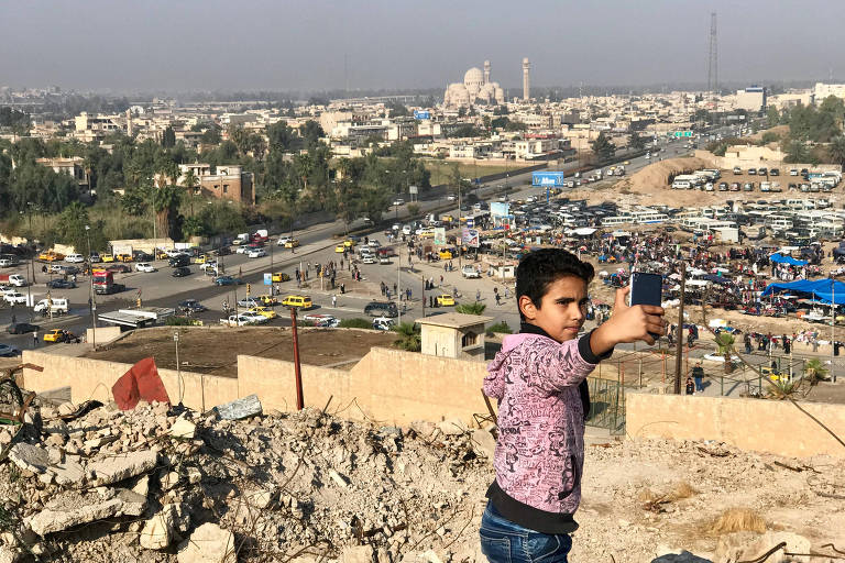 Menino faz selfie com vista para Mossul no topo da montanha de ruínas da mesquita de Jonas, destruída pela facção Estado Islâmico
