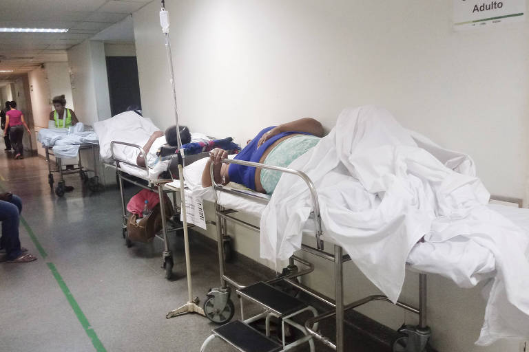 Pacientes sobre macas espalhadas pelo corredor do hospital