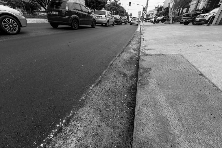 Foto mostra asfalto com carros em segundo plano
