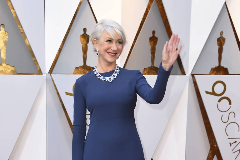 Com vestido longo azul, Atriz Helen Mirren acena em cima do tapete vermelho do Oscar