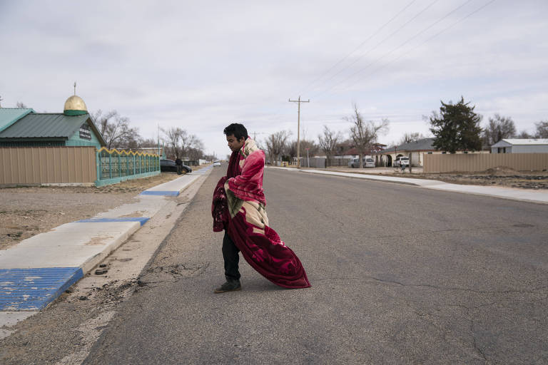 Homem com cobertor atravessa rua de Cactus, no Texas (EUA) 