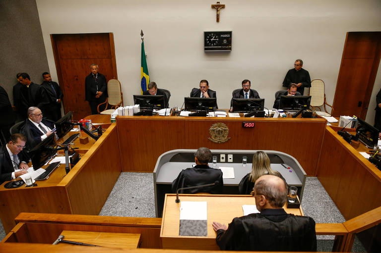 Ministros em torno de uma mesa de madeira realizando julgamento