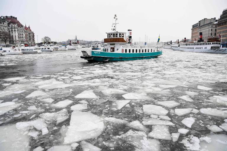 Barco navega na baía de Nybroviken, na capital sueca, Estocolmo, durante o inverno