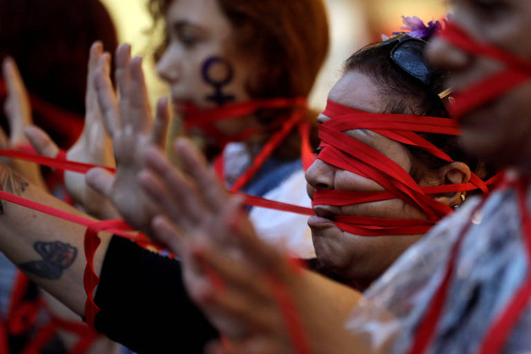 Mulheres usam fitas vermelhas em seus rostos durante marcha do Dia Internacional da Mulher na avenida Paulista, em São Paulo
