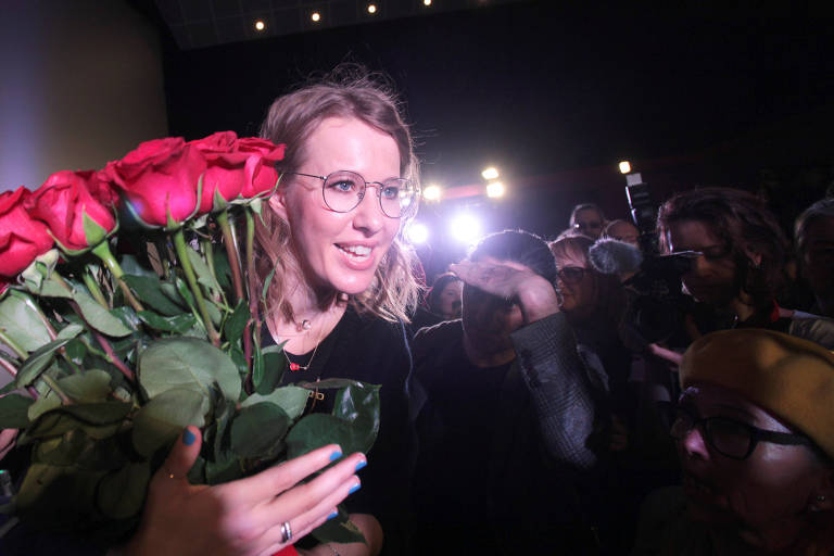 Carregando buquê de rosas, a candidata presidencial Ksenia Sobchak passa por seguidores e fotógrafos após comício na cidade de Irkutsk, na Sibéria