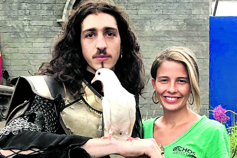 Débora ensina Johnny Massaro a lidar com o pombo Hector, que é  pombo-correio em "Deus Salve o Rei"