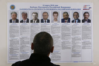FILE PHOTO: A voter looks through a broadsheet with information about the candidates during the early voting ahead of the March 18 presidential election in Nenets Autonomous District