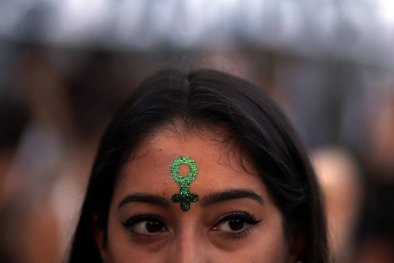 Mulher com símbolo feminino pintado na testa durante o Dia Internacional da Mulher de 2018, em Buenos Aires, na Argentina