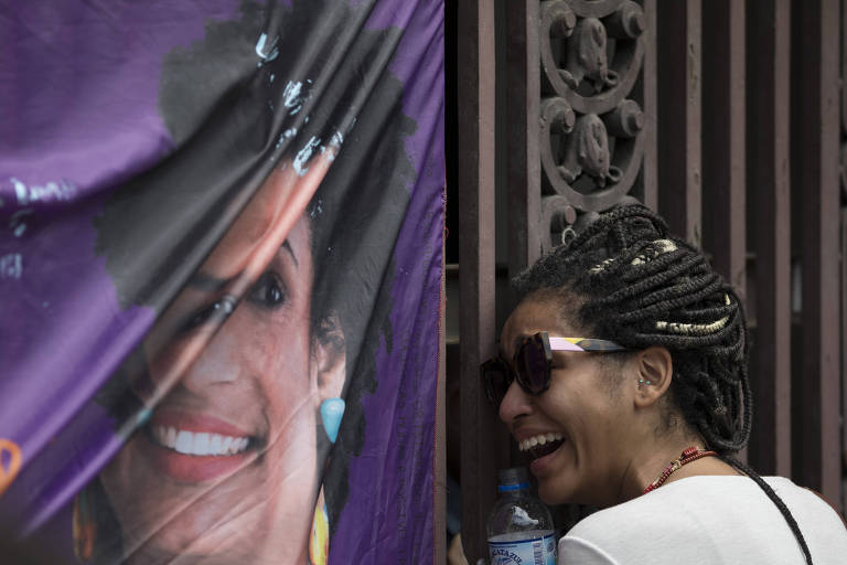 Mulher chora ao lado de banner com a imagem da vereadora Marielle Franco (PSOL) , assassinada no Rio na quarta (14)
