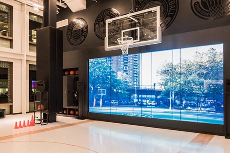A quadra de basquete da loja Nike Soho, em Nova York, com piso claro e um telão atrás da cesta