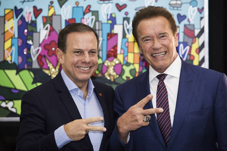O prefeito de SP João Doria (PSDB) e o ex-governador da Califórnia Arnold Schwarzenegger posam reproduzindo o símbolo "Acelera SP"