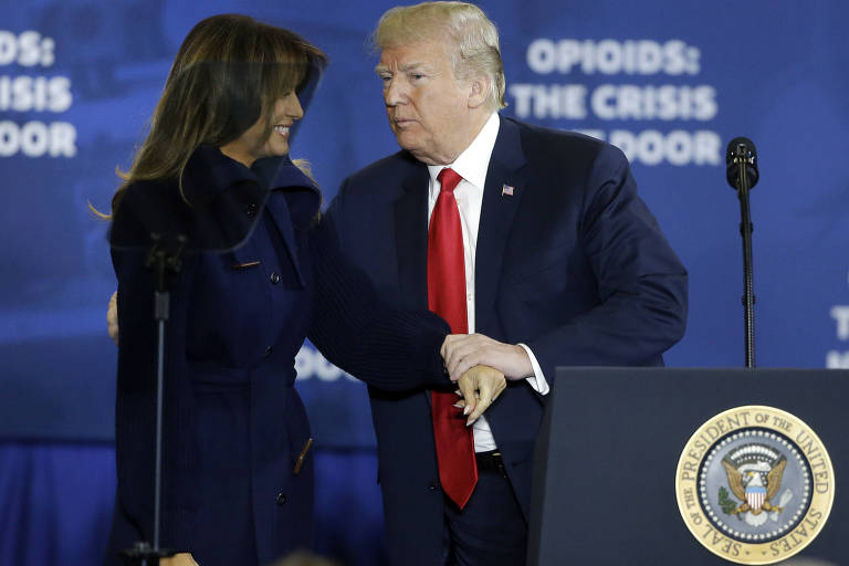 Donald Trump segura a mão da primeira-dama, Melania, ao subir ao pódio da escola técnica de Manchester, New Hmpshire, onde anunciou programa de combate às drogas