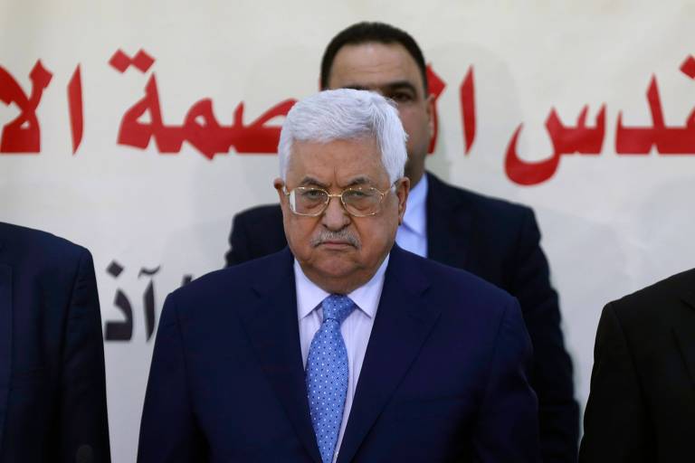 À frente de outros três homens de terno, o presidente palestino, Mahmoud Abbas, aparece sério no palco de um evento do Fatah no início de março em Ramallah, na Cisjordânia