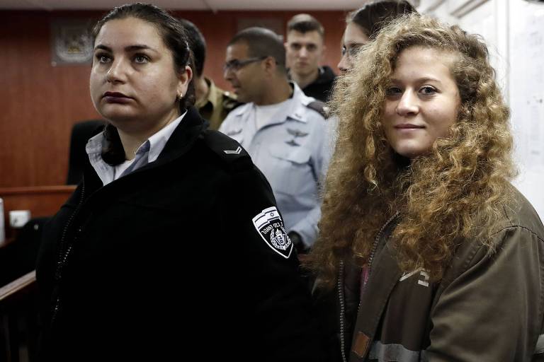 Acompanhada de policial israelense, a palestina Ahed Tamimi (dir.) participa de sessão de seu julgamento em fevereiro 