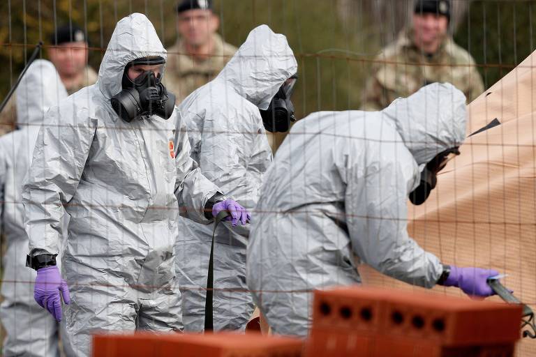 Com roupas especiais, militares britânicos trabalham para descontaminar um veículo atingido pelo agente químico usado contra o ex-espião russo Serguei Skripal em Salisbury, na Inglaterra