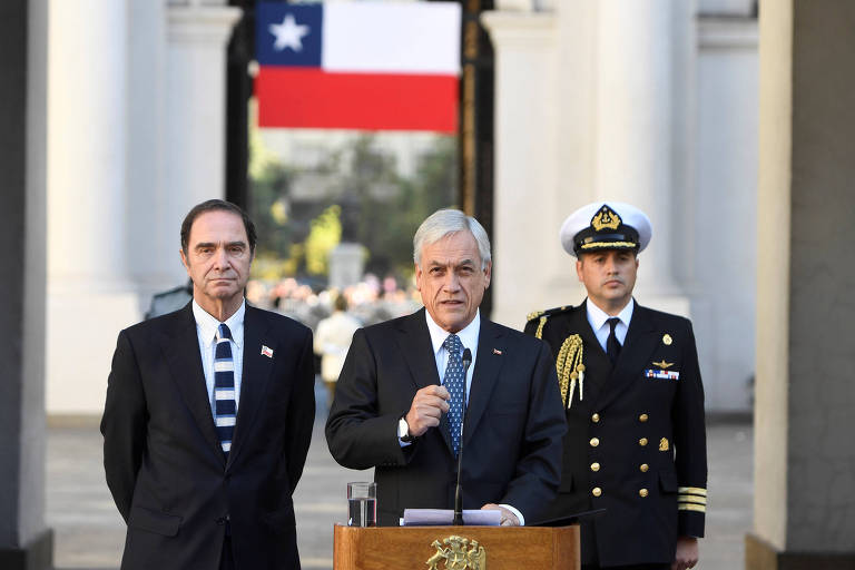 Ao lado do ministro da Justiça, Hernán Larraín (à esq.), o presidente do Chile, Sebastián Piñera, faz pronunciamento em Santiago na quinta-feira (22)