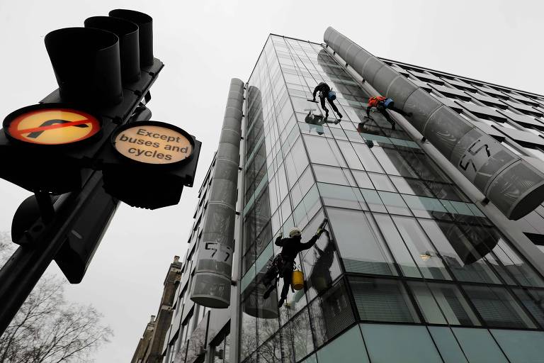 Homens limpam vidros no prédio onde fica a sede da Cambridge Analytica em Londres; empresa usou estrangeiros na eleição americana 