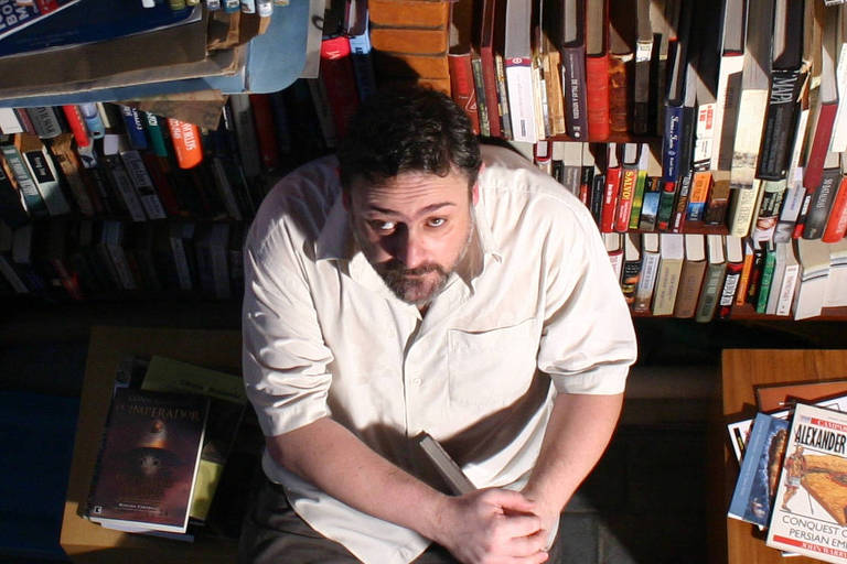O jornalista Ricardo Bonalume, sentado diante de uma estante de livros em sua casa em São Paulo, em foto de 2005