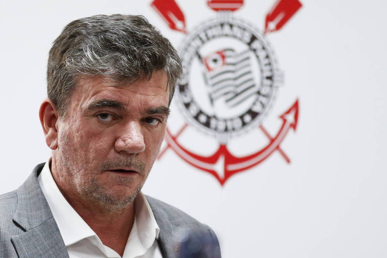O presidente do Corinthians, Andrés Sanchez, sai de entrevista coletiva após ser eleito. Atrás dele, um fundo com escudo do Corinthians