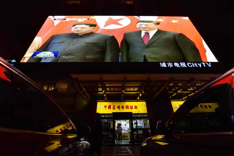 Telão em cima de restaurante em Pequim exibe a imagem do encontro entre Xi Jinping e Kim Jong-un 