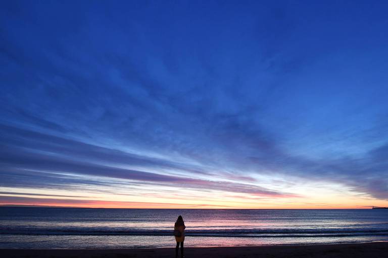 Pessoa assiste ao nascer do sol no mar Mediterrâneo, na região de Valência (Espanha)