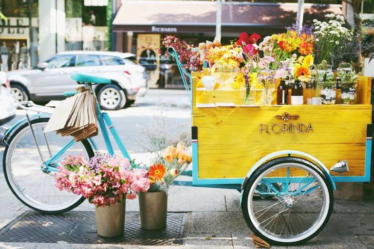 A 'flower bike' da Florinda, loja de flores de São Paulo, em tons de azul com uma carreta amarela que leva as flores