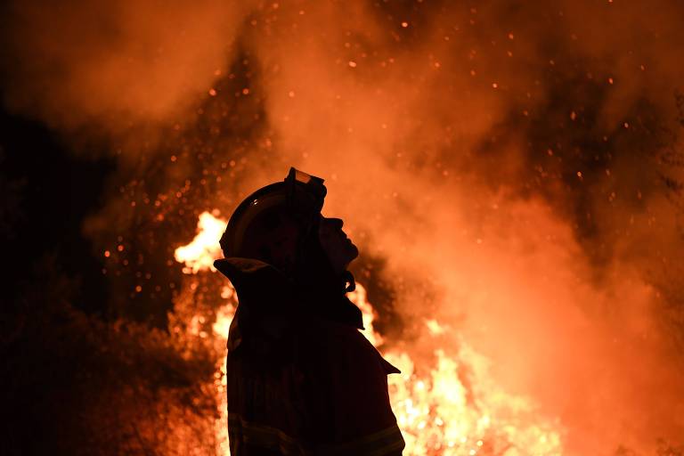 Bombeiro aparece sombreado entre chamas e fumaça de incêndio em Portugal
