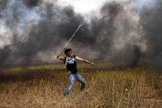 Palestinian hurls stones at Israeli troops during clashes, during a tent city protest along the Israel border with Gaza, demanding the right to return to their homeland, the southern Gaza Strip
