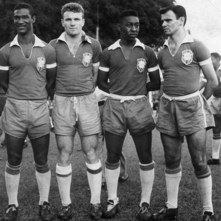 Foto preto e branca, com quatro homens de shorts e camisa