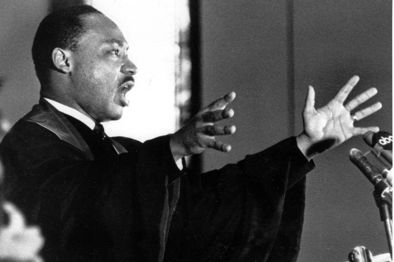Martin Luther King Jr. levanta os braços durante culto