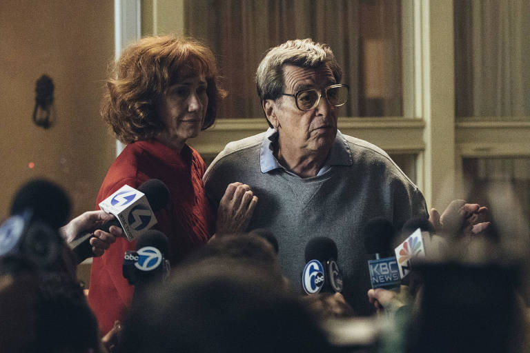 Kathy Baker e Al Pacino diante de vários jornalistas com microfones em cena de "Paterno", filme da HBO
