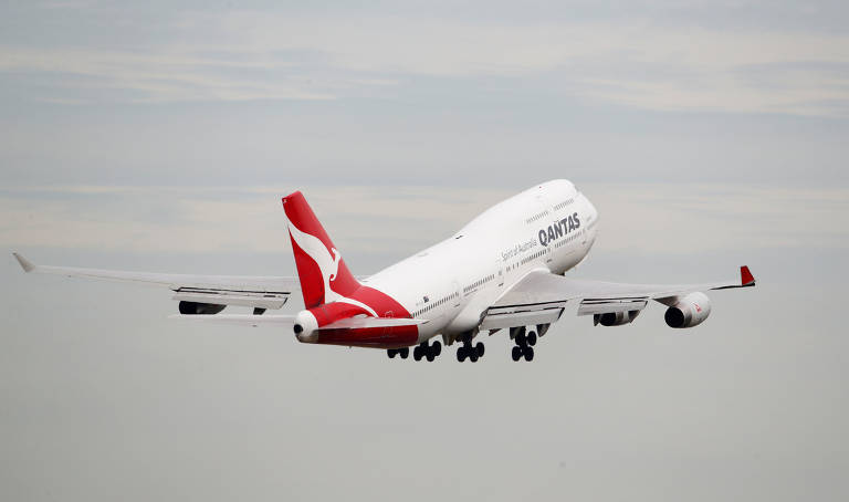 Avião da companhia aérea Qantas é mostrado por trás durante a decolagem, já no ar