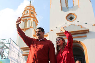 Venezuela's President Nicolas Maduro waves next to his wife Cilia Flores as they arrive for a rally with supporters in Caracas