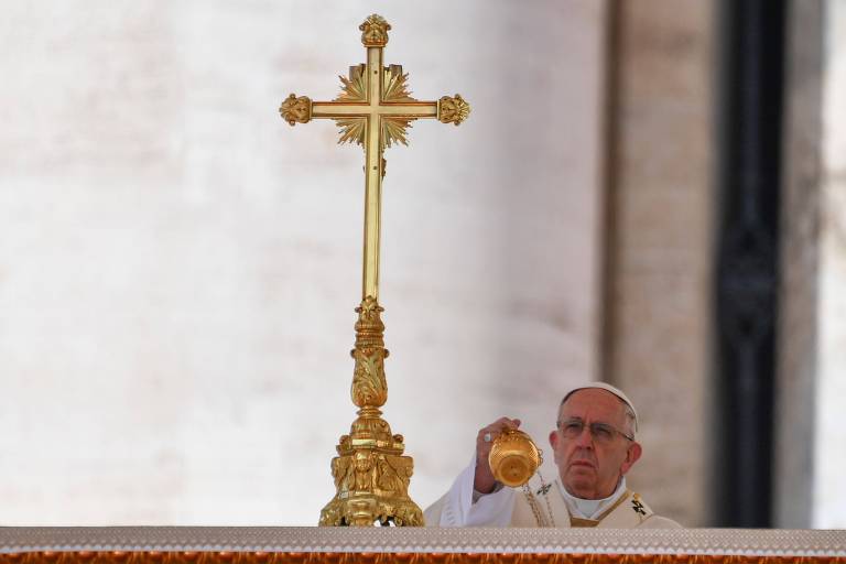 O papa Francisco ao lado de uma cruz dourada