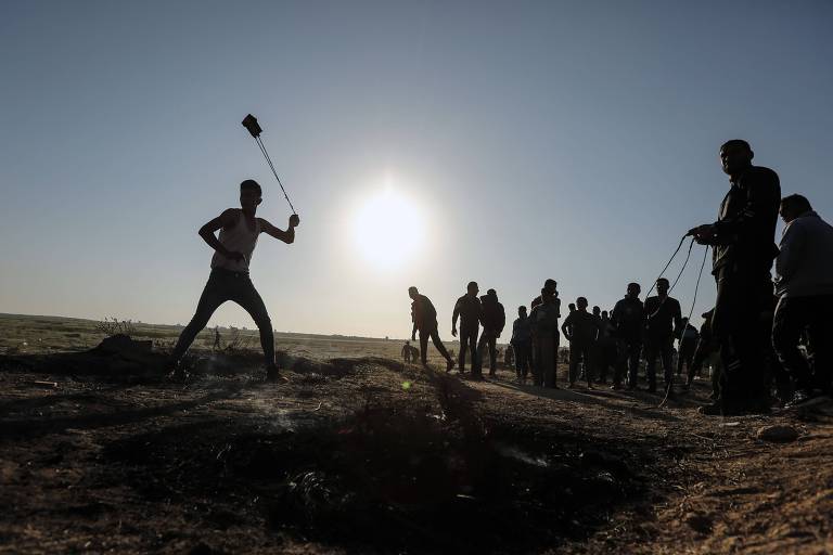 Palestinos atiram pedras contra forças israelenses em confronto na faixa de Gaza, em 31 de março