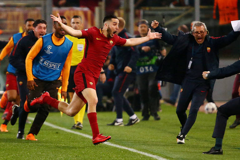 Manolas corre com os braços abertos, seguido por jogadores do banco de reservas, para comemorar o terceiro gol da Roma