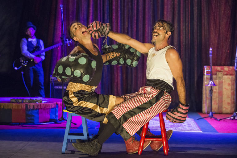 Sentados e caracterizados como palhaços, artistas do Circo Zanni trocam socos em cena, no picadeiro 