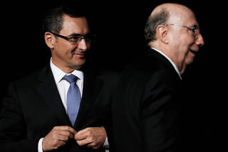 Brazil's new FM Eduardo Guardia looks at his predecessor Henrique Meirelles during the handover ceremony for the new Financial Minister in Brasilia