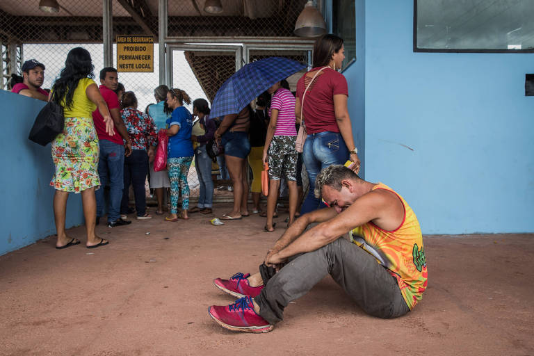 Homem chora sentado no chão em meio a outros parentes de presos que aguardam notícias na frente do Centro de Recuperação Penitenciário do Pará 3 após rebelião que deixou 21 mortos