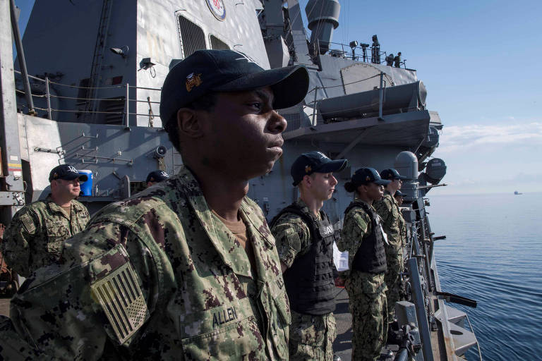 Com roupas camufladas, quatro soldados se perfilam no convés do USS Donald Cook
