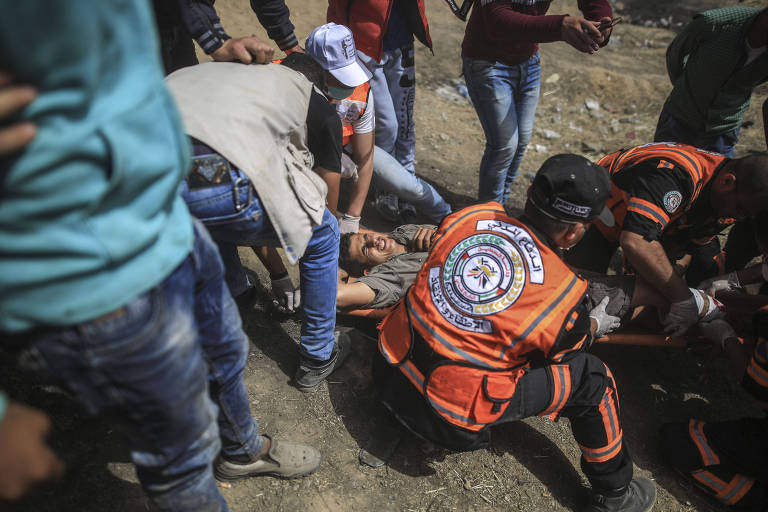 Médicos palestinos atendem um manifestante ferido durante confronto com tropas do Exército de Israel em Gaza