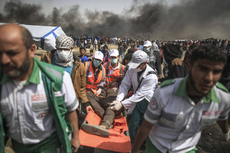 Médicos palestinos atendem um manifestante ferido durante confronto com tropas do Exército de Israel em Gaza