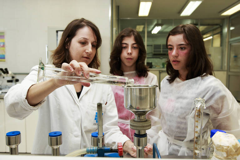 Jovens observam pesquisador fazer teste em laboratório