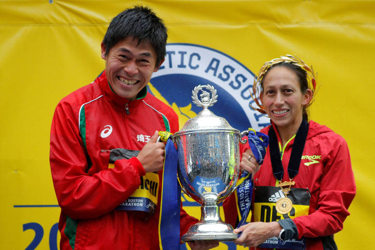 Homem e mulher sorriem enquanto seguram troféu