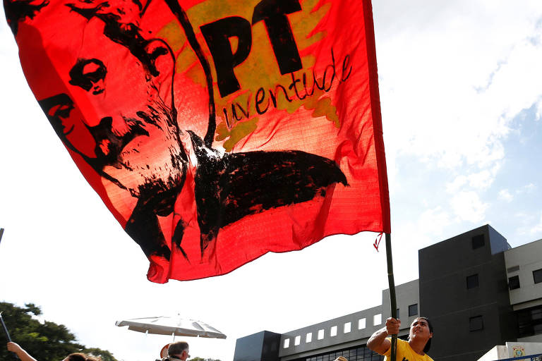 Apoiador exibe bandeira do ex-presidente Lula em frente ao prédio da Policial Federal em Curitiba 
